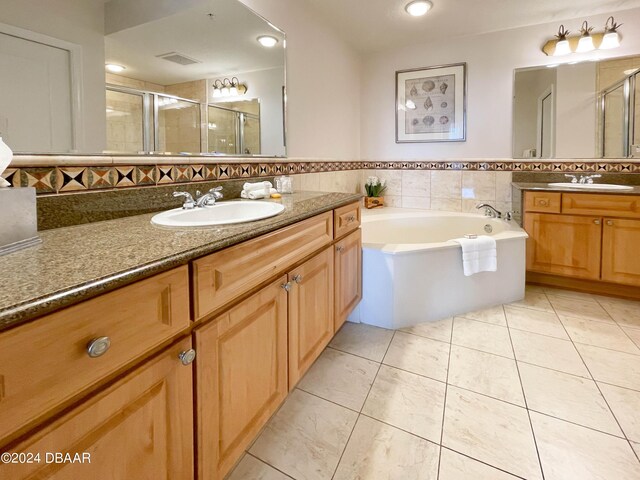 200 Ocean Crest Dr Unit 317, Palm Coast, FL 32137 - bathroom featuring a stall shower, tile patterned floors, two vanities, a garden tub, and tile walls