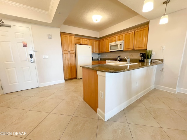 kitchen with sink, kitchen peninsula, a textured ceiling, white appliances, and pendant lighting