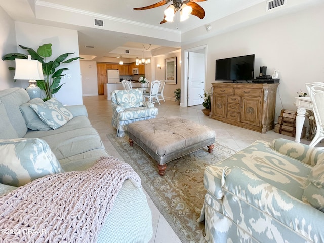 tiled living room featuring ceiling fan with notable chandelier, a raised ceiling, and ornamental molding