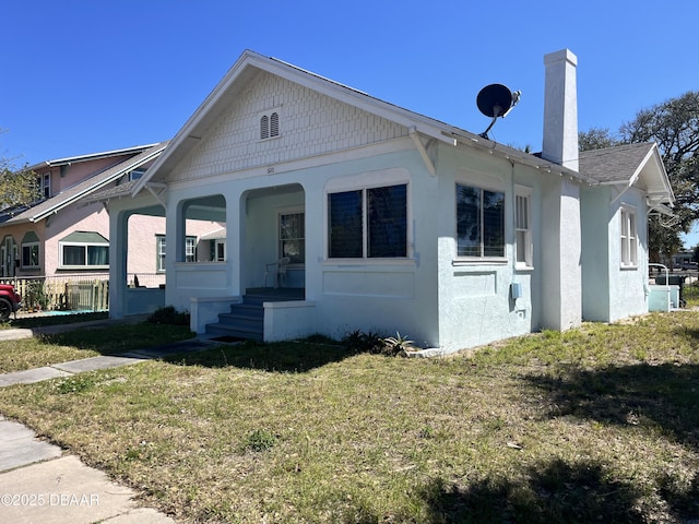 view of front of property featuring stucco siding, a chimney, and a front yard