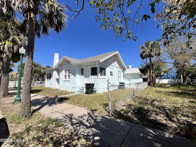 view of front of home featuring stucco siding, a chimney, and fence