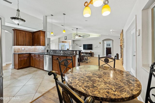 kitchen featuring decorative backsplash, stainless steel dishwasher, dark stone counters, ceiling fan, and decorative light fixtures