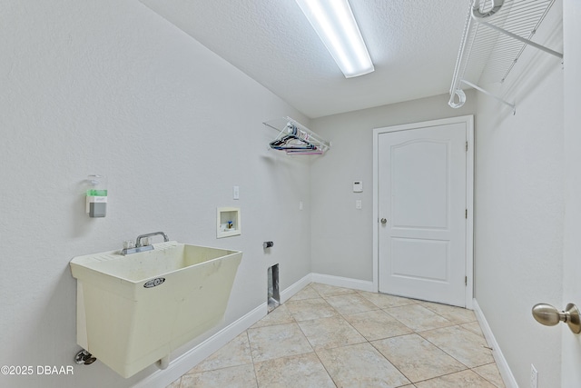 washroom featuring a textured ceiling, light tile patterned floors, sink, and hookup for a washing machine