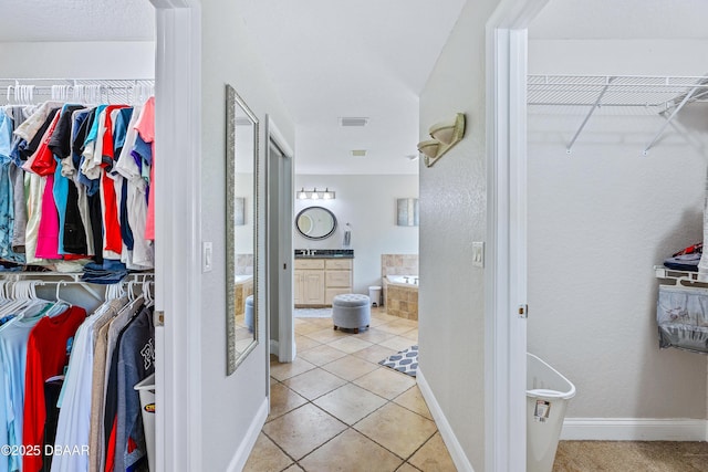 walk in closet with light tile patterned floors and sink