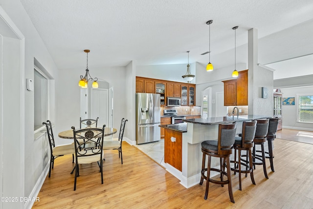 kitchen with a breakfast bar, sink, vaulted ceiling, appliances with stainless steel finishes, and kitchen peninsula