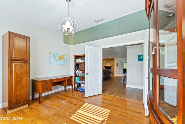 interior space featuring a chandelier, light hardwood / wood-style floors, and a stone fireplace