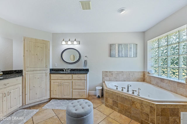 bathroom with tile patterned floors, vanity, and tiled tub