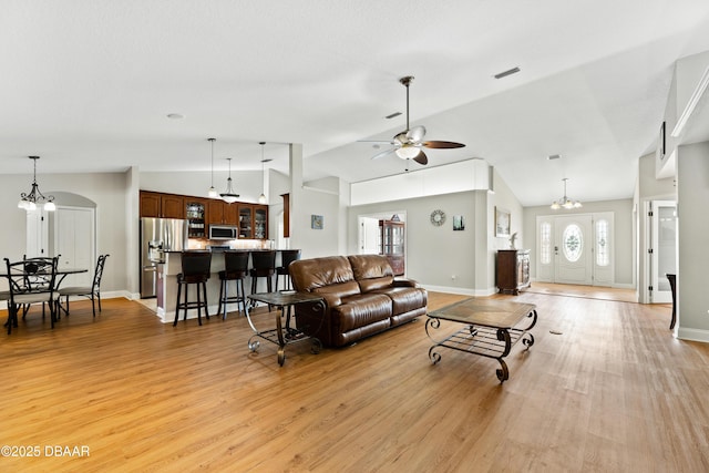 living room featuring ceiling fan with notable chandelier, light hardwood / wood-style floors, and lofted ceiling