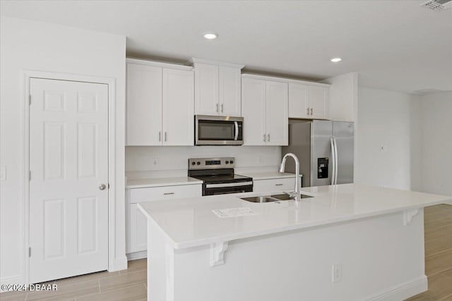 kitchen with light hardwood / wood-style flooring, sink, a center island with sink, and stainless steel appliances