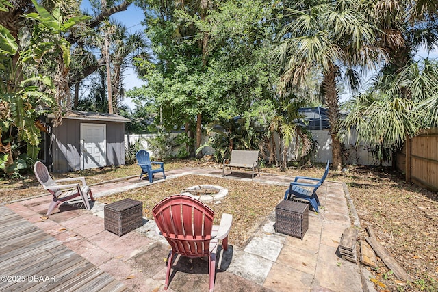 view of patio / terrace with a fenced backyard, an outdoor fire pit, a storage shed, and an outbuilding