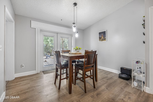 dining area with baseboards, french doors, a textured ceiling, and wood finished floors