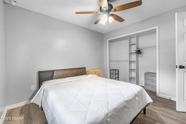 bedroom featuring baseboards, a closet, a textured ceiling, and wood finished floors