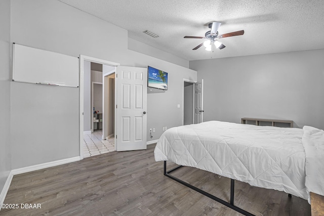 bedroom with baseboards, visible vents, a textured ceiling, and wood finished floors