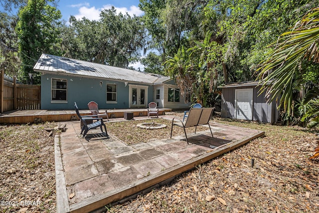 exterior space with metal roof, an outdoor structure, a wooden deck, a fire pit, and a storage unit