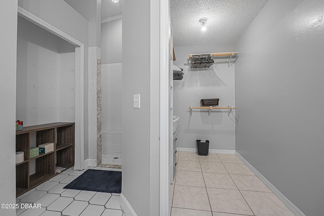 full bath with a walk in closet, tile patterned floors, a textured ceiling, and a shower stall