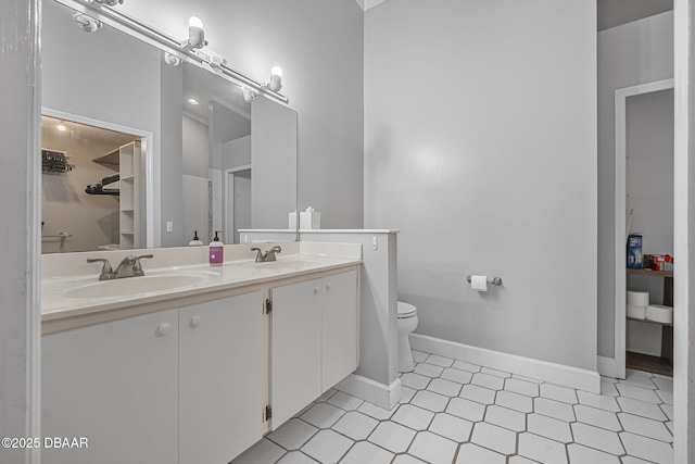 full bathroom with double vanity, toilet, baseboards, and a sink