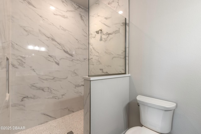 bathroom with a tile shower and toilet