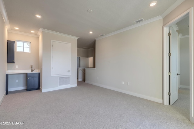 unfurnished living room with light carpet, built in desk, crown molding, and sink