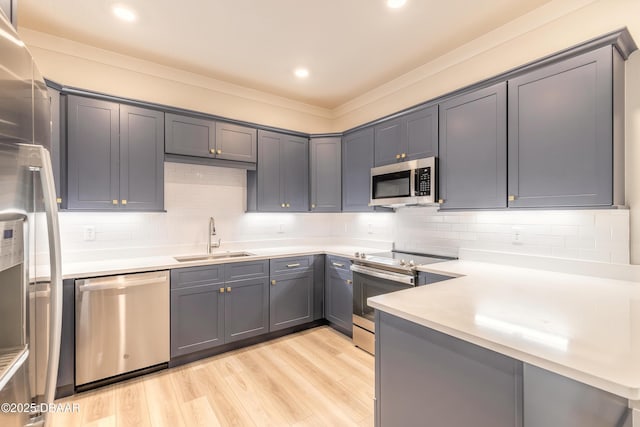 kitchen featuring appliances with stainless steel finishes, light hardwood / wood-style flooring, gray cabinetry, and sink