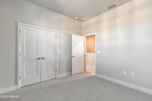 unfurnished bedroom featuring light colored carpet and a closet