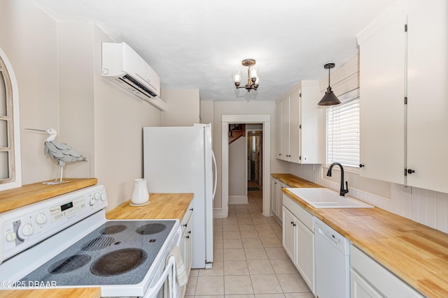 kitchen with butcher block counters, an AC wall unit, white cabinetry, a sink, and white appliances