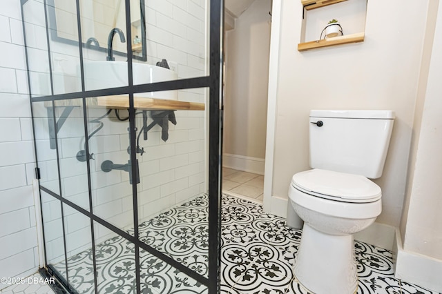 full bathroom with toilet, tile patterned flooring, baseboards, and tiled shower