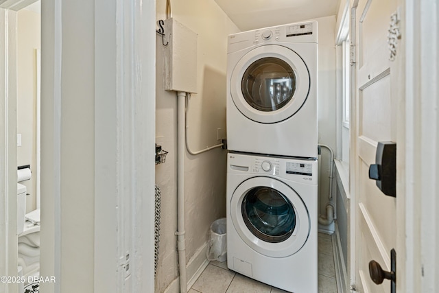 clothes washing area featuring stacked washer and dryer, light tile patterned flooring, and laundry area