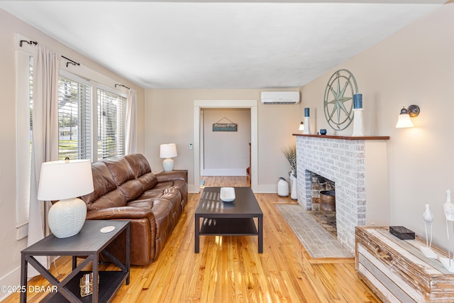 living area featuring an AC wall unit, a fireplace, wood finished floors, and baseboards