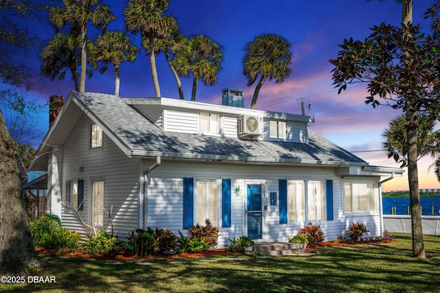 view of front of house featuring ac unit, roof with shingles, a chimney, and a front lawn