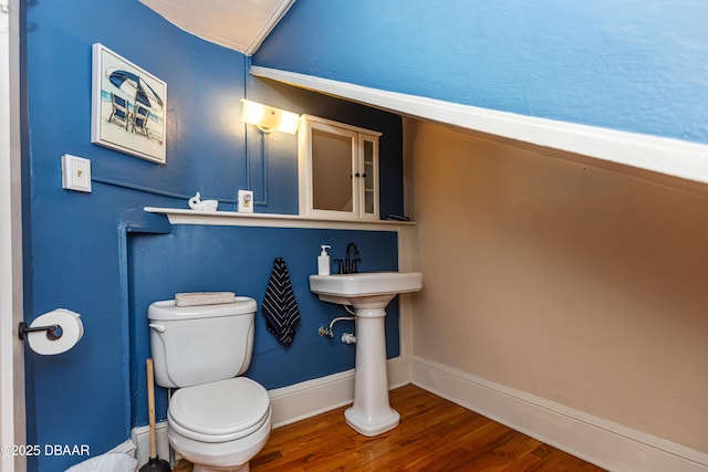 half bathroom with wood finished floors, toilet, and baseboards