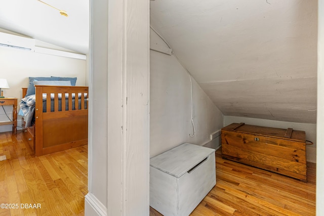 bonus room featuring lofted ceiling, an AC wall unit, and wood finished floors