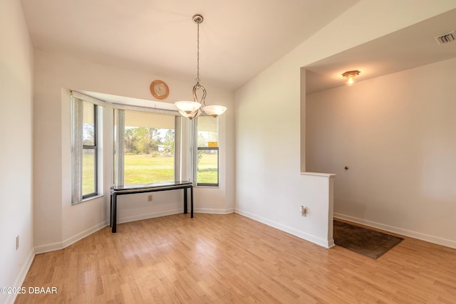 unfurnished room with lofted ceiling, a chandelier, and light wood-type flooring