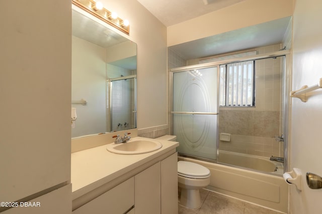 full bathroom featuring vanity, tile patterned floors, shower / bath combination with glass door, and toilet