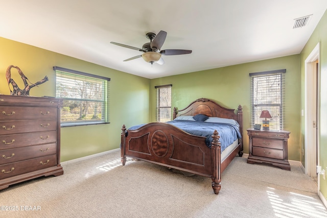 bedroom with multiple windows, light carpet, and ceiling fan