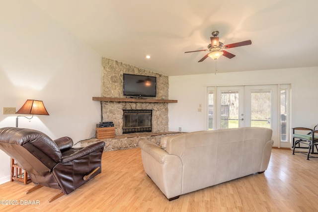 living room featuring a fireplace, light hardwood / wood-style floors, french doors, and ceiling fan