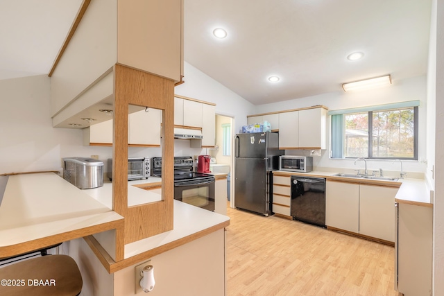 kitchen featuring vaulted ceiling, sink, white cabinets, black appliances, and light wood-type flooring