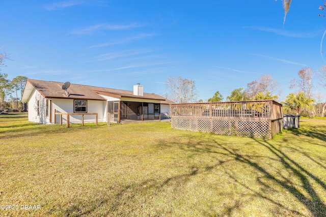 back of property with a wooden deck and a lawn