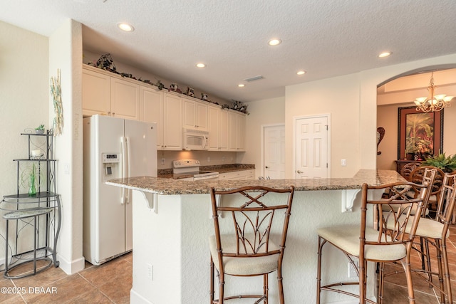 59 Westland Run, Ormond Beach, FL 32174 - kitchen featuring white appliances, arched walkways, recessed lighting, a breakfast bar area, and stone countertops