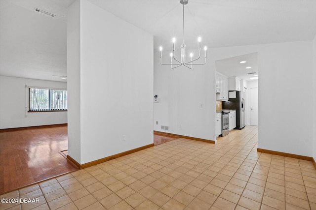 unfurnished dining area with a chandelier, vaulted ceiling, and light hardwood / wood-style flooring