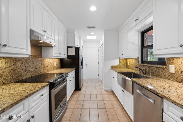 kitchen featuring decorative backsplash, light stone countertops, white cabinetry, and stainless steel appliances