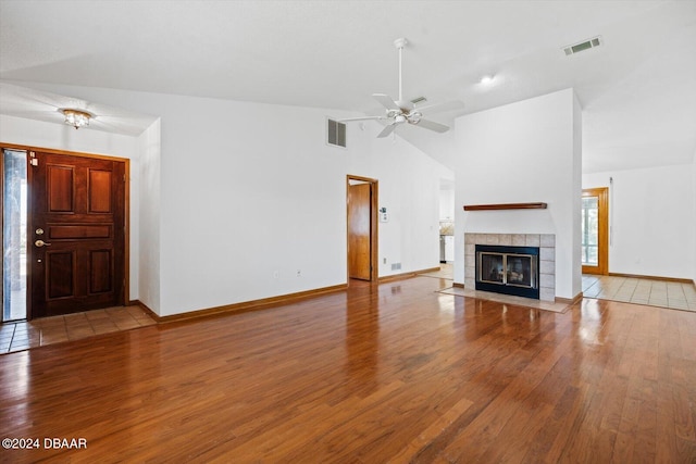 unfurnished living room with a tile fireplace, ceiling fan, lofted ceiling, and hardwood / wood-style flooring