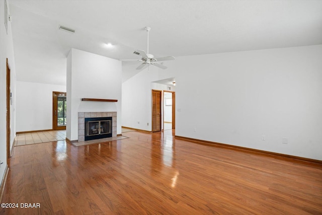 unfurnished living room with light wood-type flooring, vaulted ceiling, ceiling fan, and a tiled fireplace