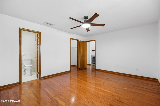 unfurnished bedroom with a closet, ceiling fan, ensuite bathroom, and wood-type flooring