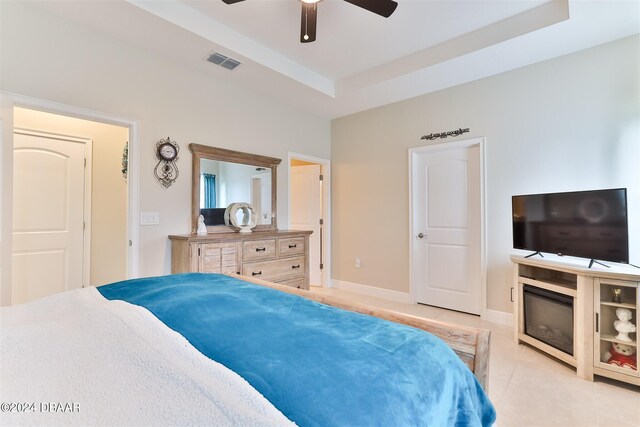 bedroom with ceiling fan, light tile patterned floors, and a tray ceiling