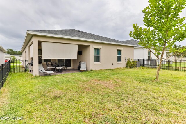 back of house featuring a patio and a yard