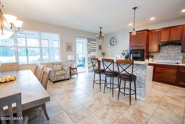 kitchen featuring black appliances, decorative backsplash, hanging light fixtures, and an inviting chandelier