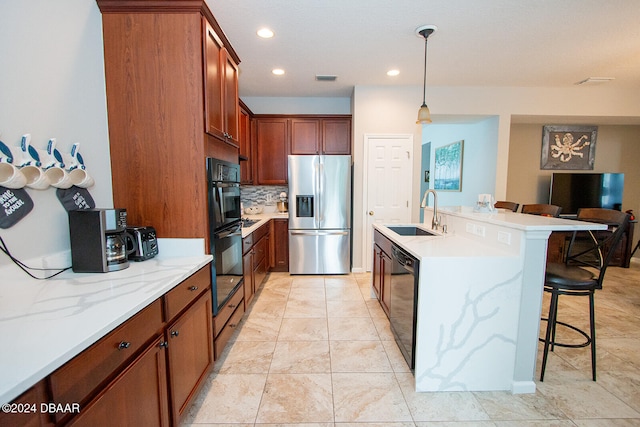 kitchen with sink, black appliances, a kitchen bar, backsplash, and hanging light fixtures