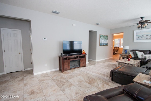 living area with baseboards, visible vents, ceiling fan, and a textured ceiling