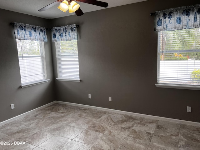 unfurnished room featuring a ceiling fan and baseboards