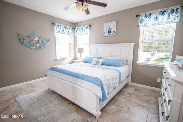 bedroom featuring ceiling fan, multiple windows, and baseboards